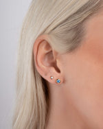 Gold stud earrings on model featuring gemstone earrings with the march birthstone and dainty stud earrings to follow