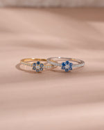 Closeup image of dainty stackable rings featuring a gold minimalist flower ring and and a matching sterling silver flower ring