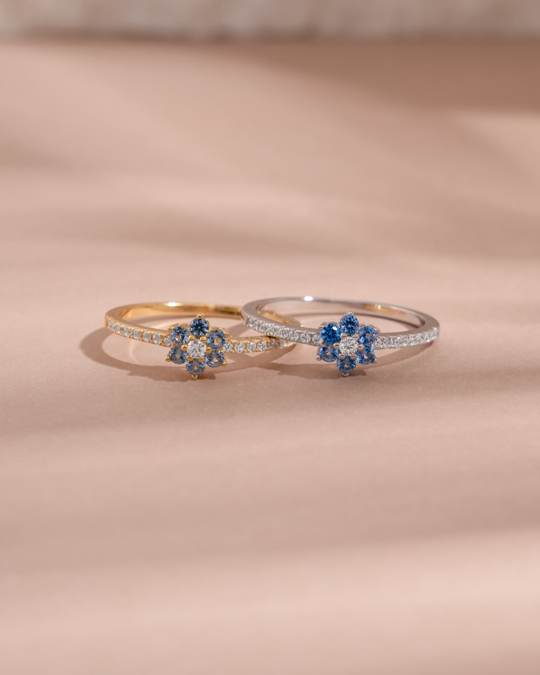 Closeup image of dainty stackable rings featuring a gold minimalist flower ring and and a matching sterling silver flower ring