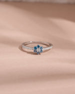 sterling silver ring with aquamarine blue gemstone on a beige fabric background