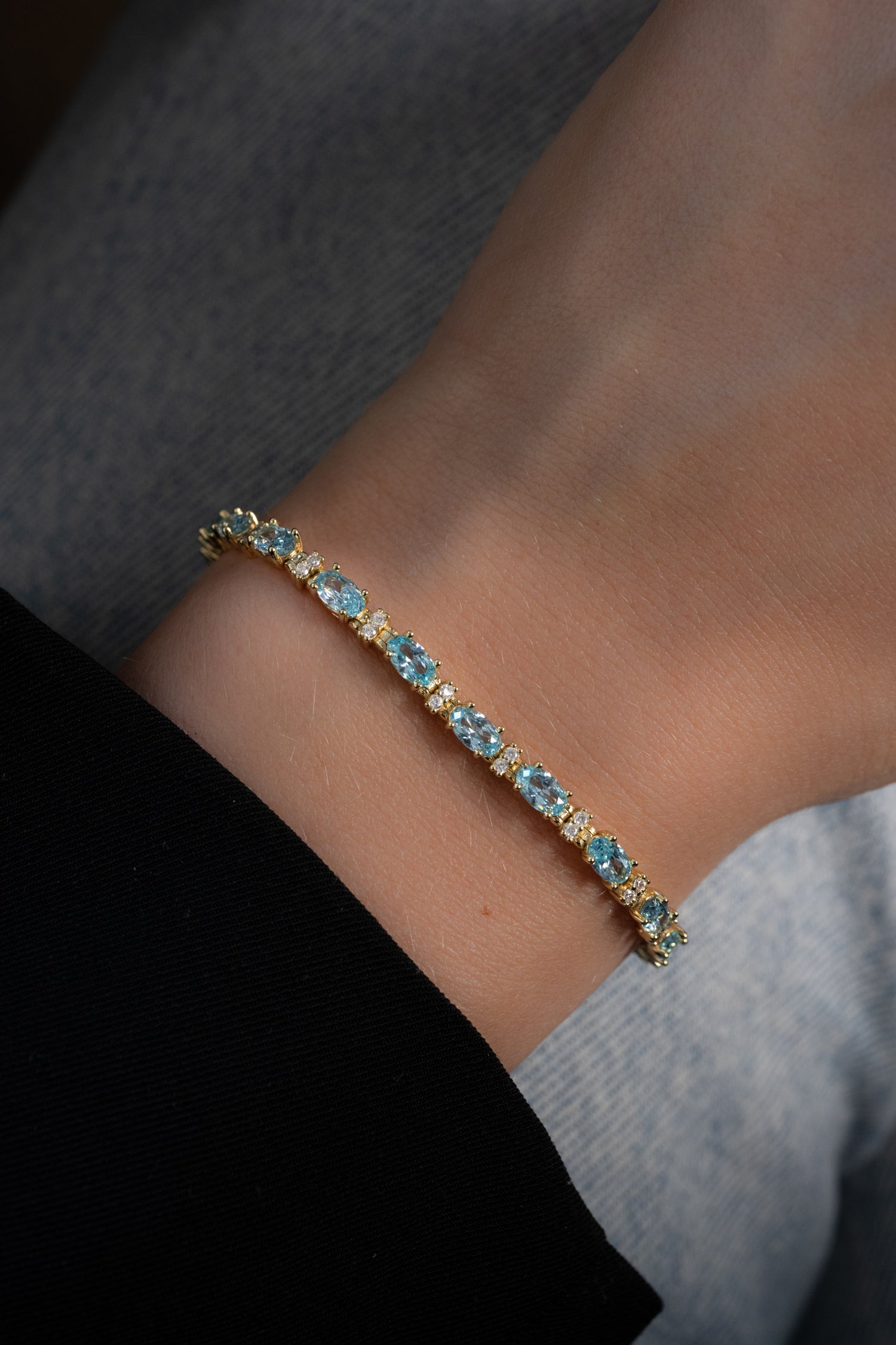 model wearing gold tennis bracelet with aquamarine stones