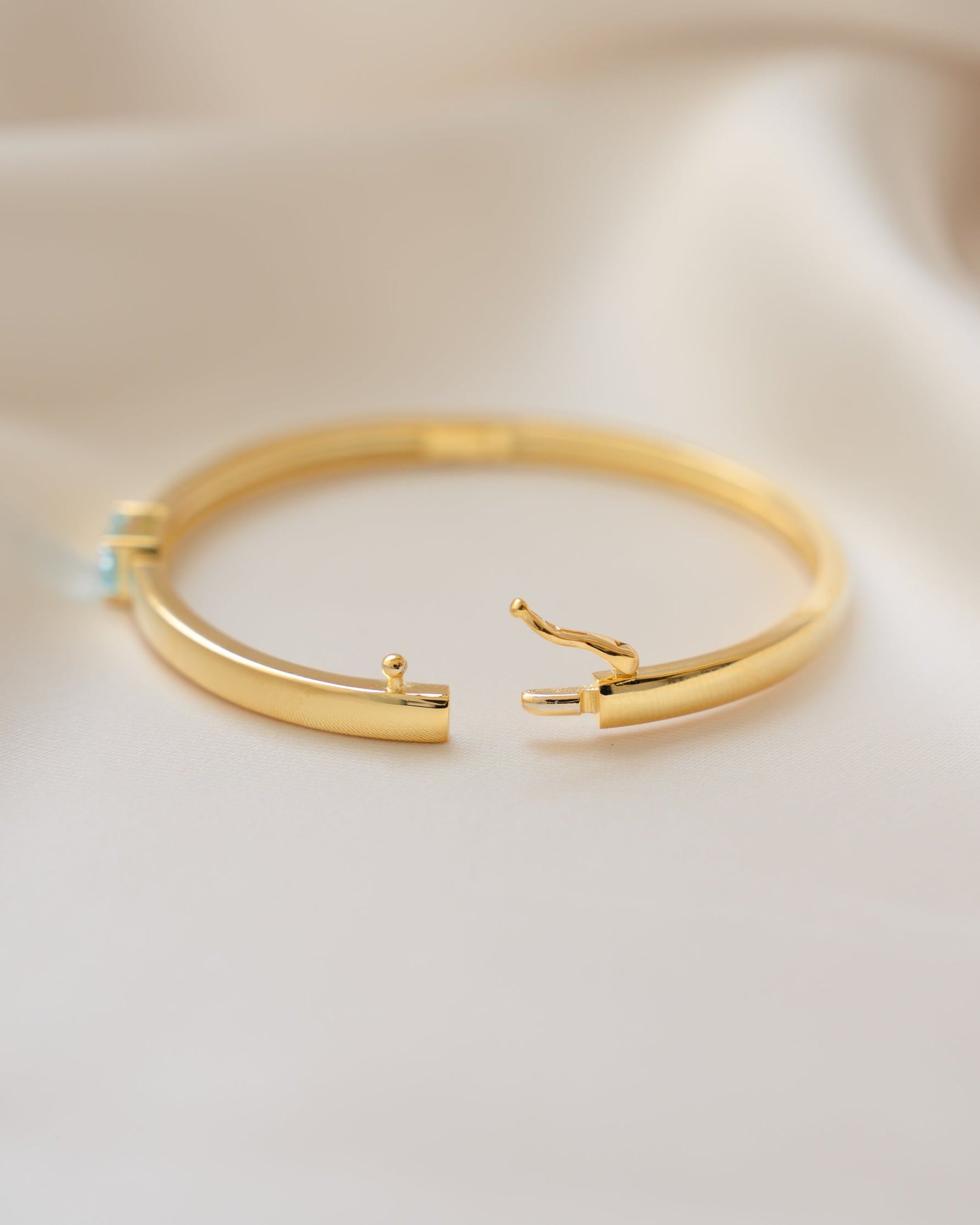 Side view of a gold bangle aquamarine bracelet, showcasing the box clasp closure style