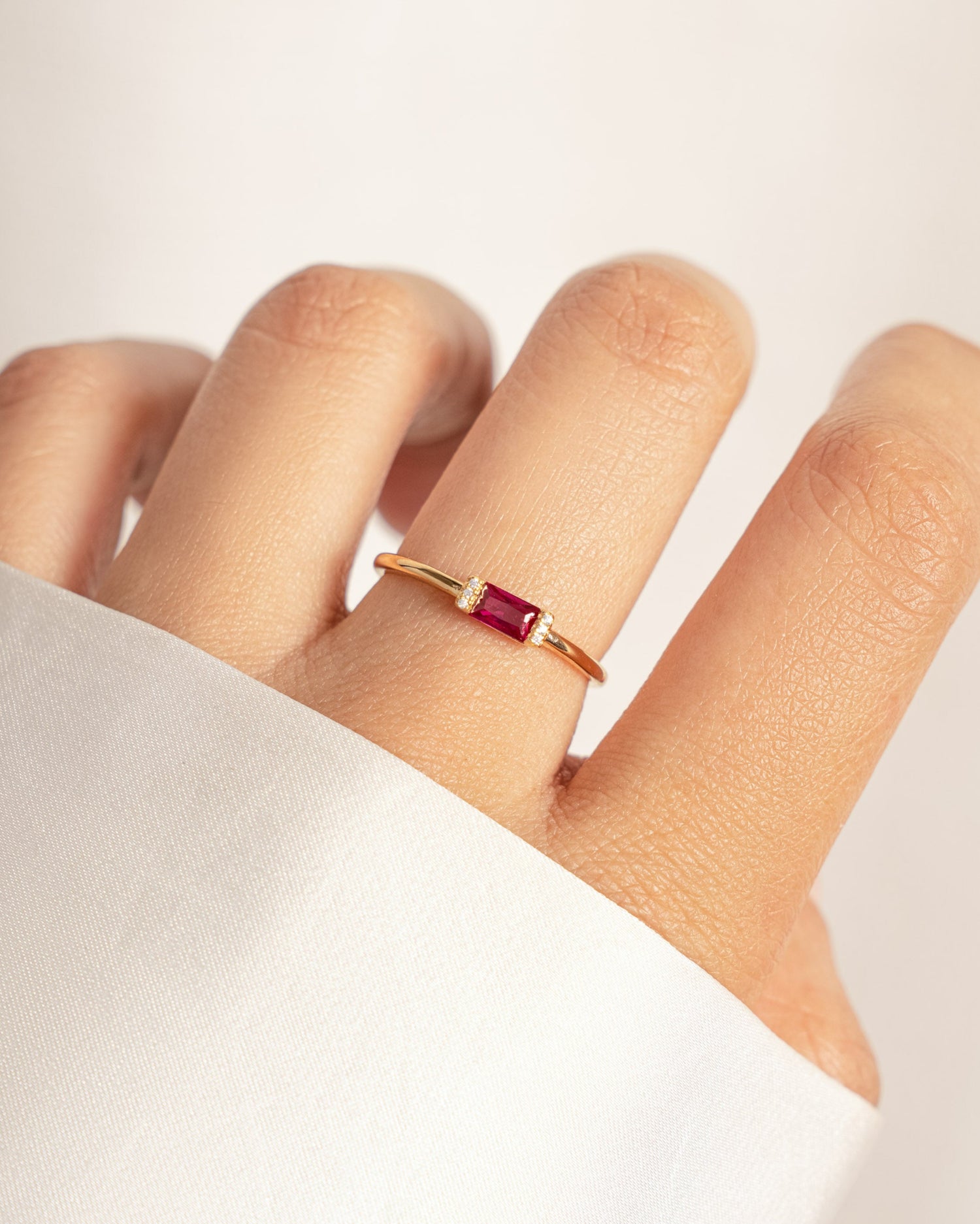 model wearing simple dainty baguette ring with ruby stone in the center