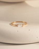 closeup image of dainty gold ring with a white cz baguette stone 