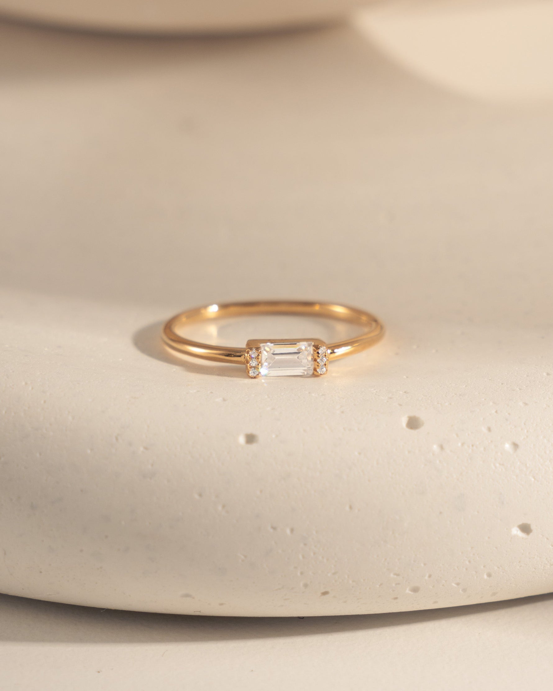 closeup image of dainty gold ring with a white cz baguette stone 