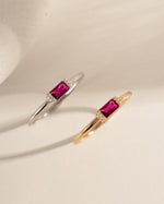 two pairs of baguette dainty rings, one in sterling silver with a ruby baguette center stone and a gold dainty ring with a ruby baguette stone