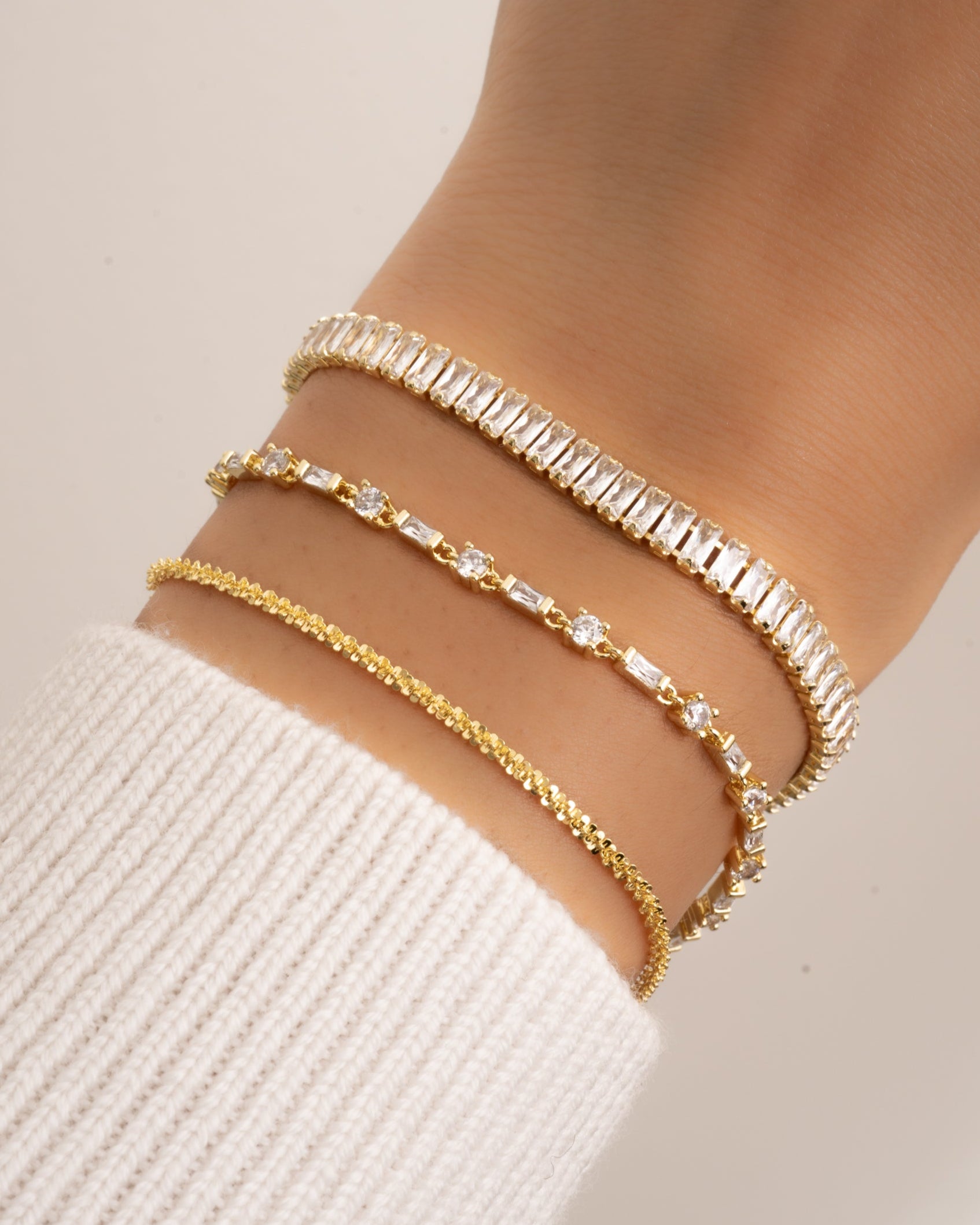 closeup image of dainty diamond stacking bracelets featuring a diamond baguette & solitaire bracelet