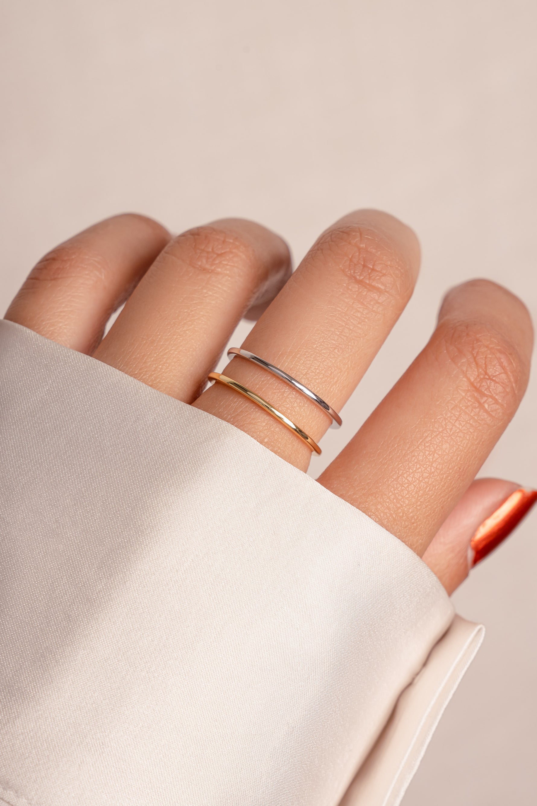 Model wearing stacked gold and silver thin plain band.