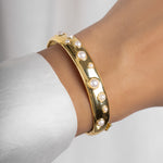 model wearing statement bracelet featuring a gold bangle bracelet with studded pearl design