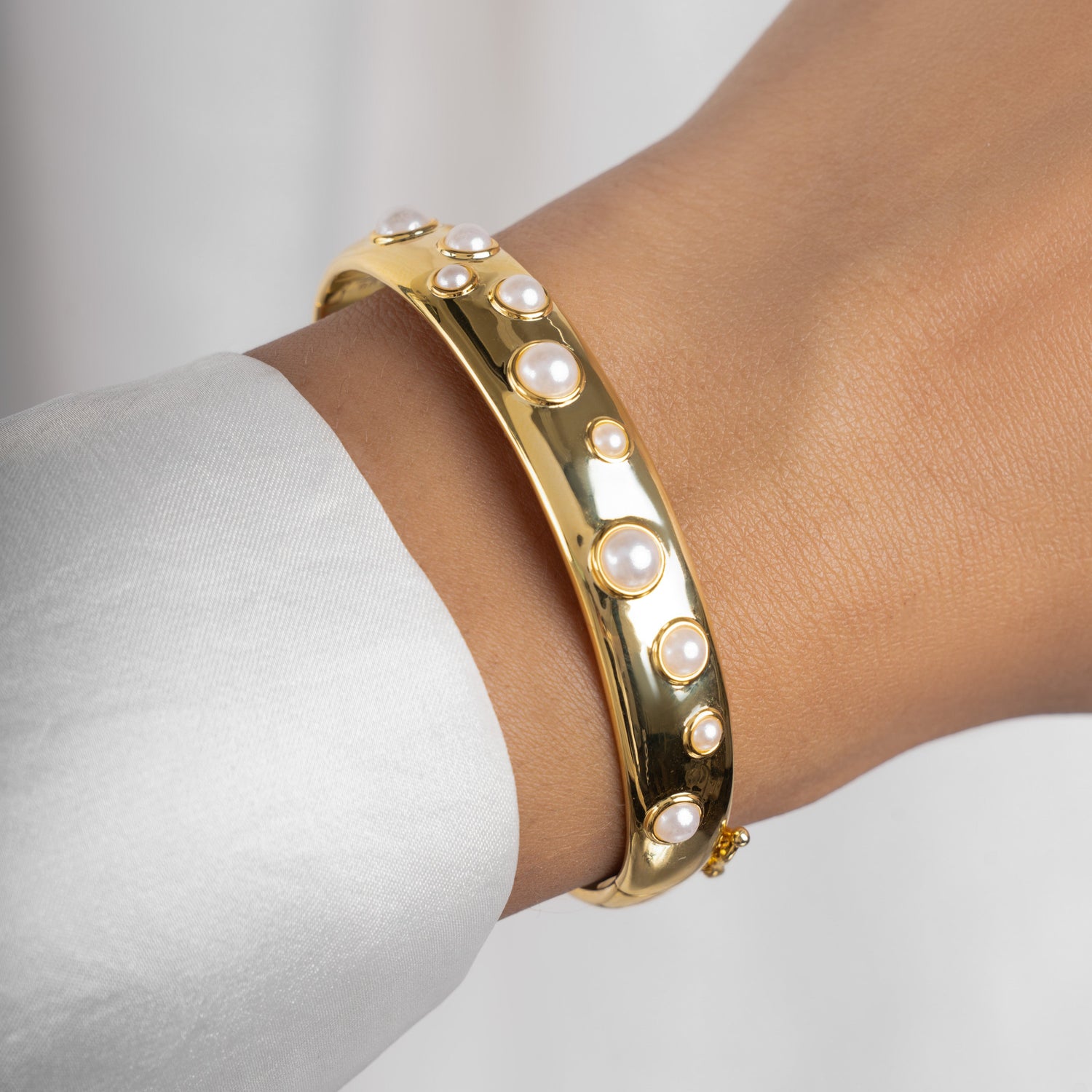 model wearing statement bracelet featuring a gold bangle bracelet with studded pearl design