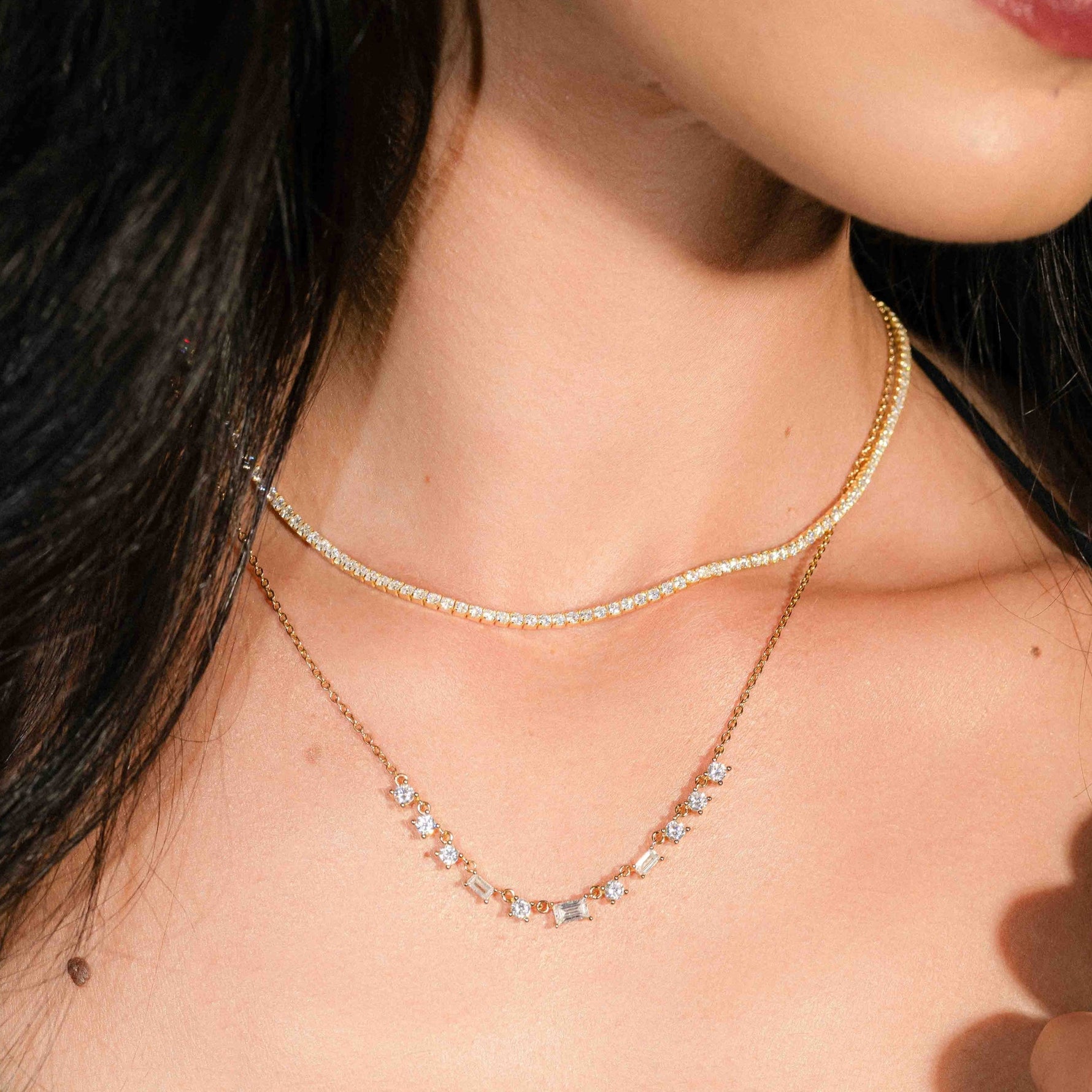 Model wearing dainty necklace with baguette diamonds in 14k gold