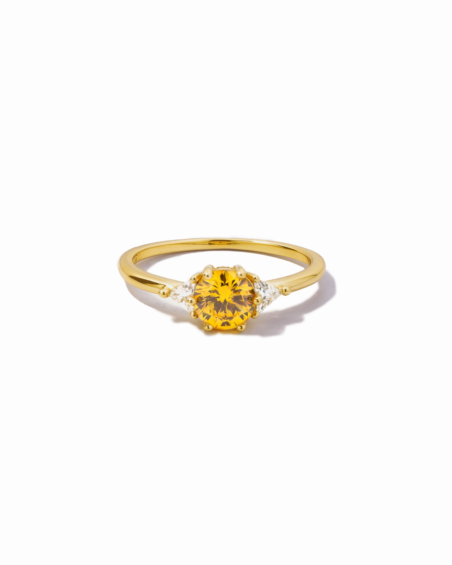 Gold ring with a yellow canary gemstone on a white background