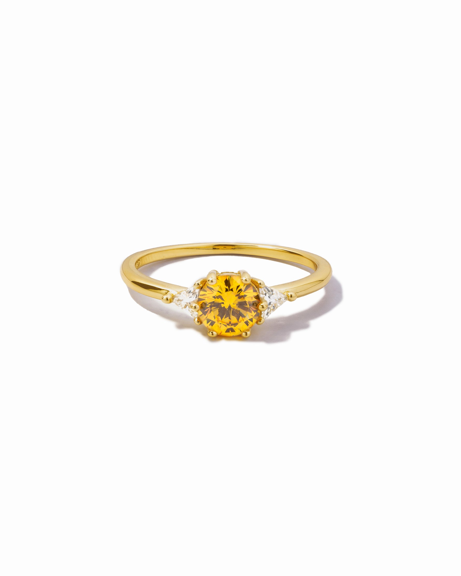 Gold ring with a yellow canary gemstone on a white background