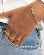 Model wearing gold chain bracelet and gold stackable rings