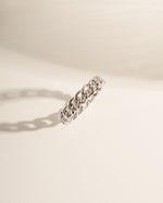 Silver ring with chain design on a light beige background