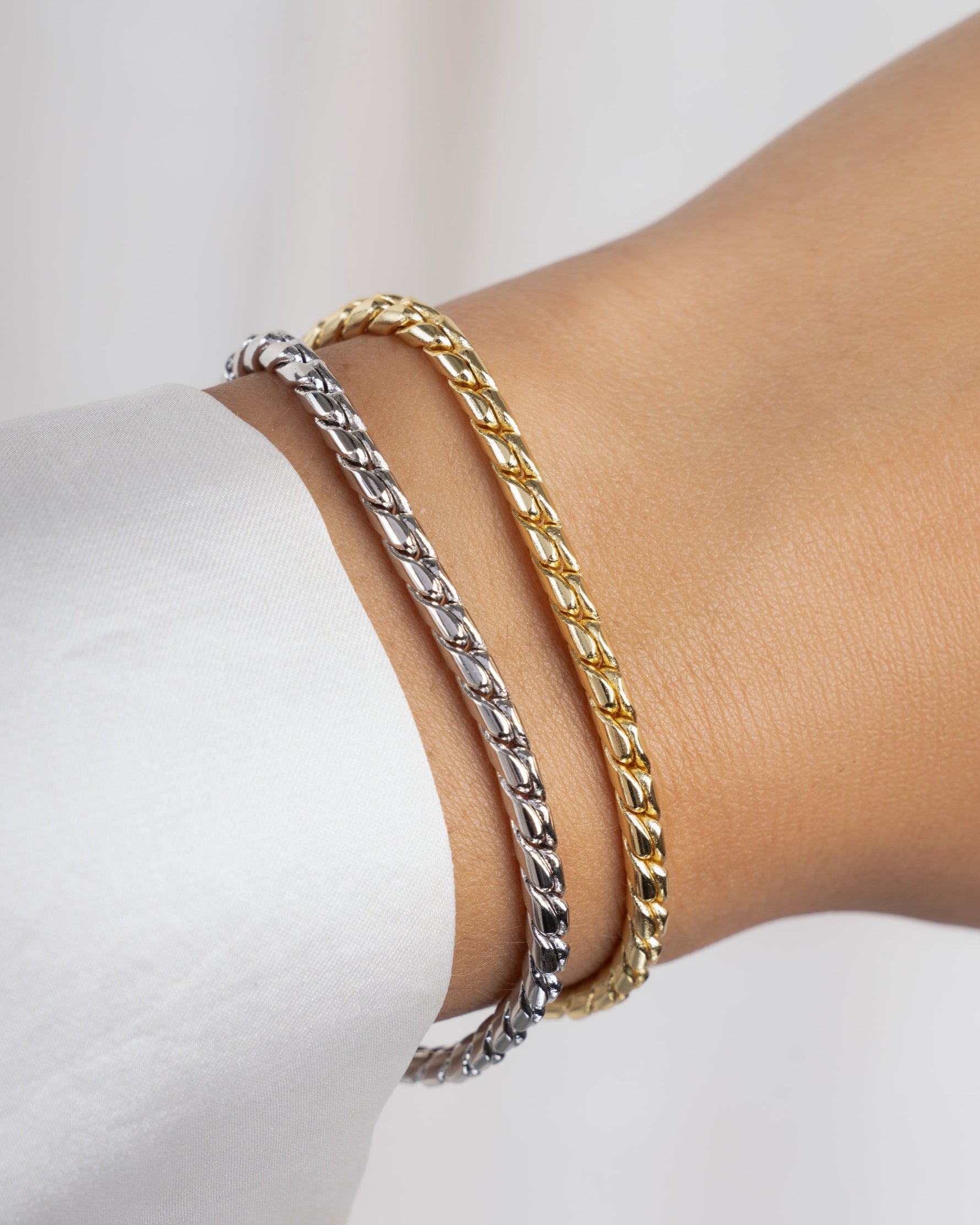 Two chain bracelets on models wrist, one silver vintage bracelet, and one gold dainty bracelet 