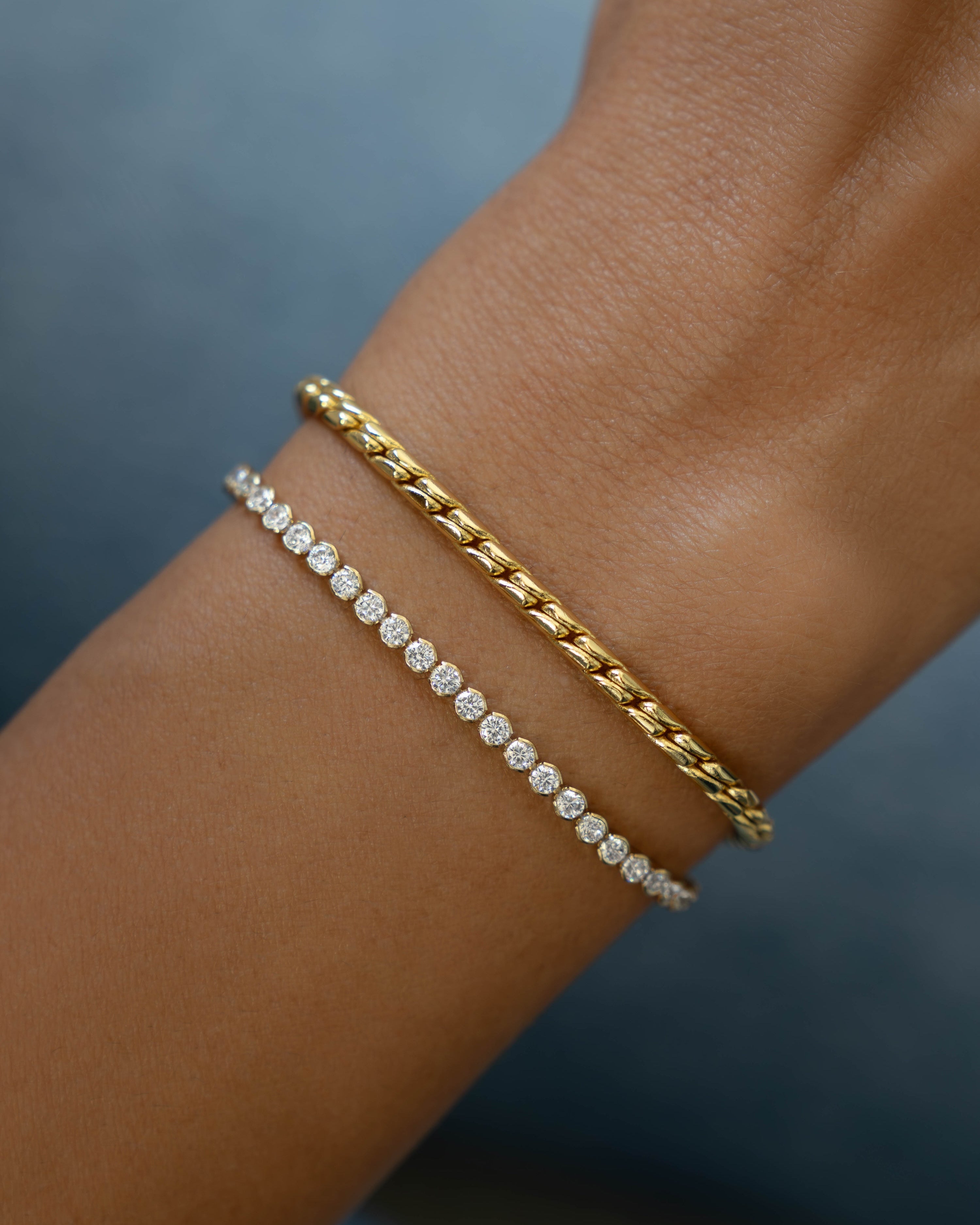 Gold diamond bracelet and gold statement bracelet stack on models wrist