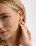 Model wearing gold unique earring stack featuring oval stud earrings, big diamond studs, and small diamond earrings