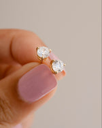 Gold studs being held in between two fingers