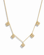 flat lay of a van cleef inspired charm necklace consisting of 5 small diamond four leaf clover charms