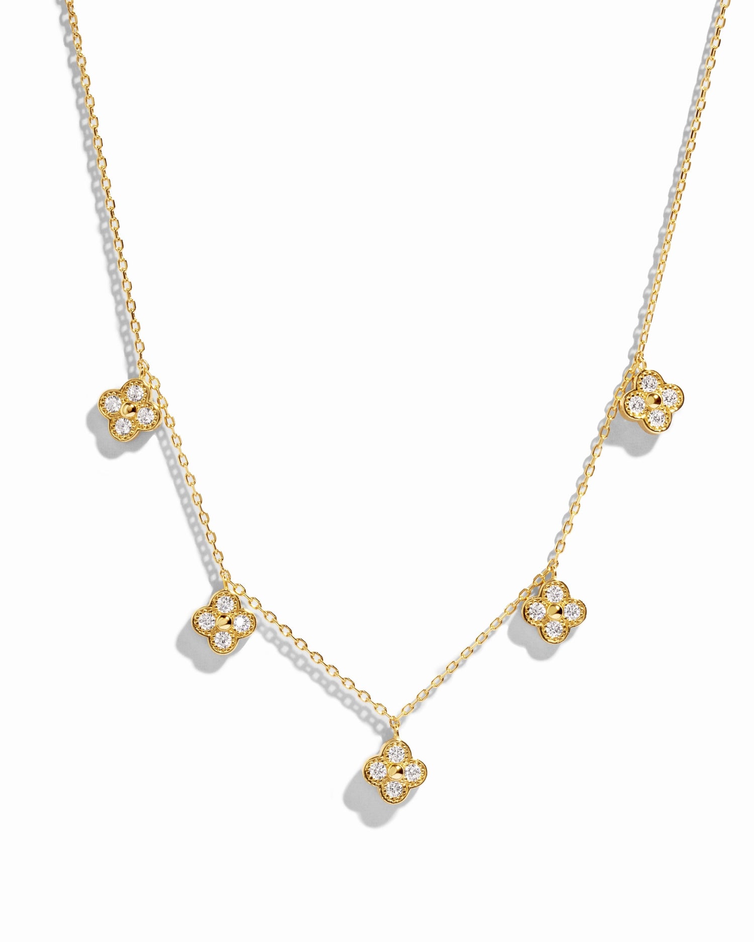 flat lay of a van cleef inspired charm necklace consisting of 5 small diamond four leaf clover charms