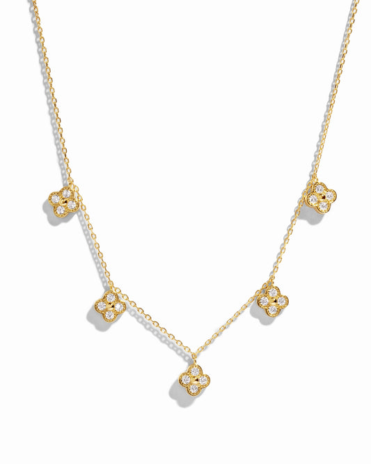 flat lay of a van cleef inspired charm necklace consisting of 5 small diamond four leaf clover charms