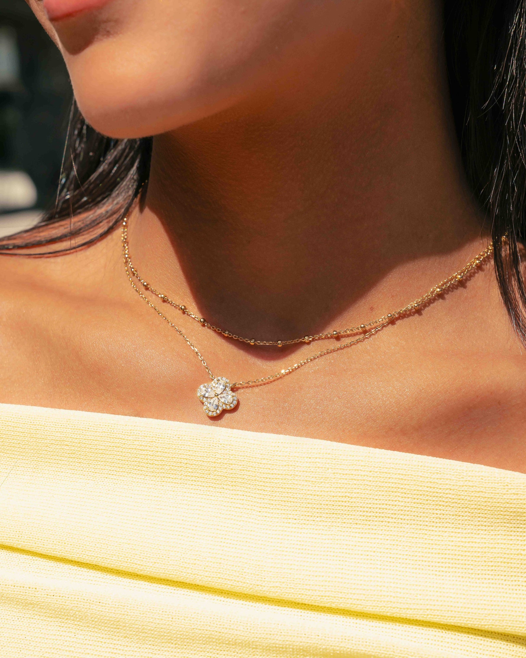 model wearing gold four leaf clover necklace paired with a simple gold beaded chain
