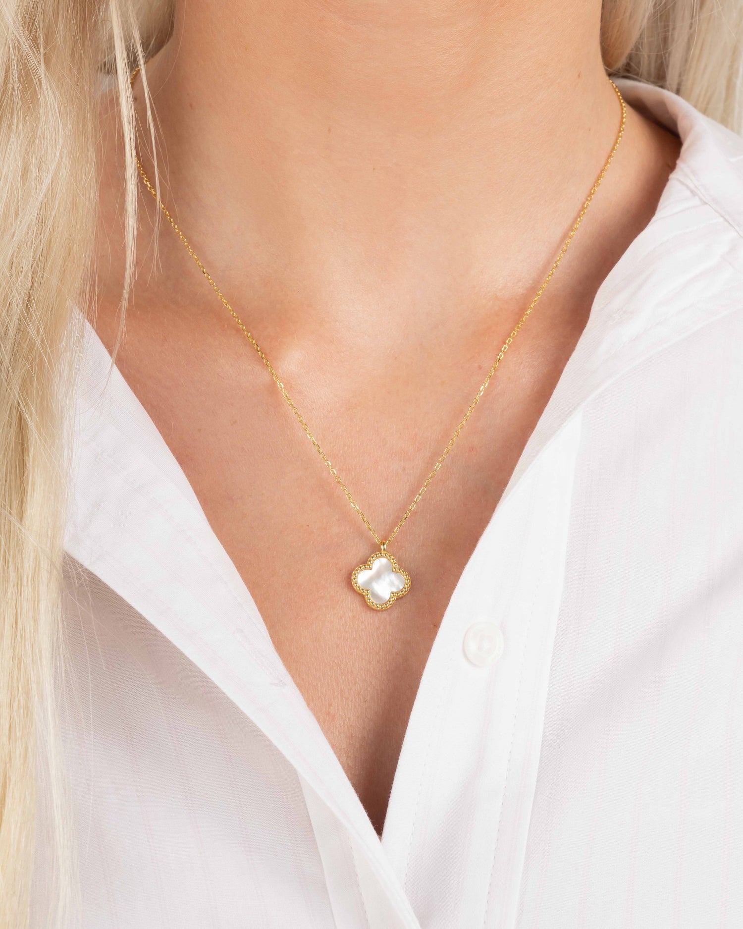 Gold necklace with a mother of pearl pendant on model