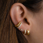 Model wearing gold earring stack featuring dainty cubic zirconia ear cuff