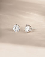 Silver bridal jewelry featuring diamond studs on a neutral background