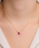 model wearing gold emerald cut and pear cut diamond toi et moi necklace with the ruby birthstone and the rose birthstone