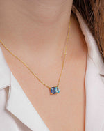 model wearing sapphire and aquamarine toi et moi necklace with a pear cut diamond and emerald cut diamond