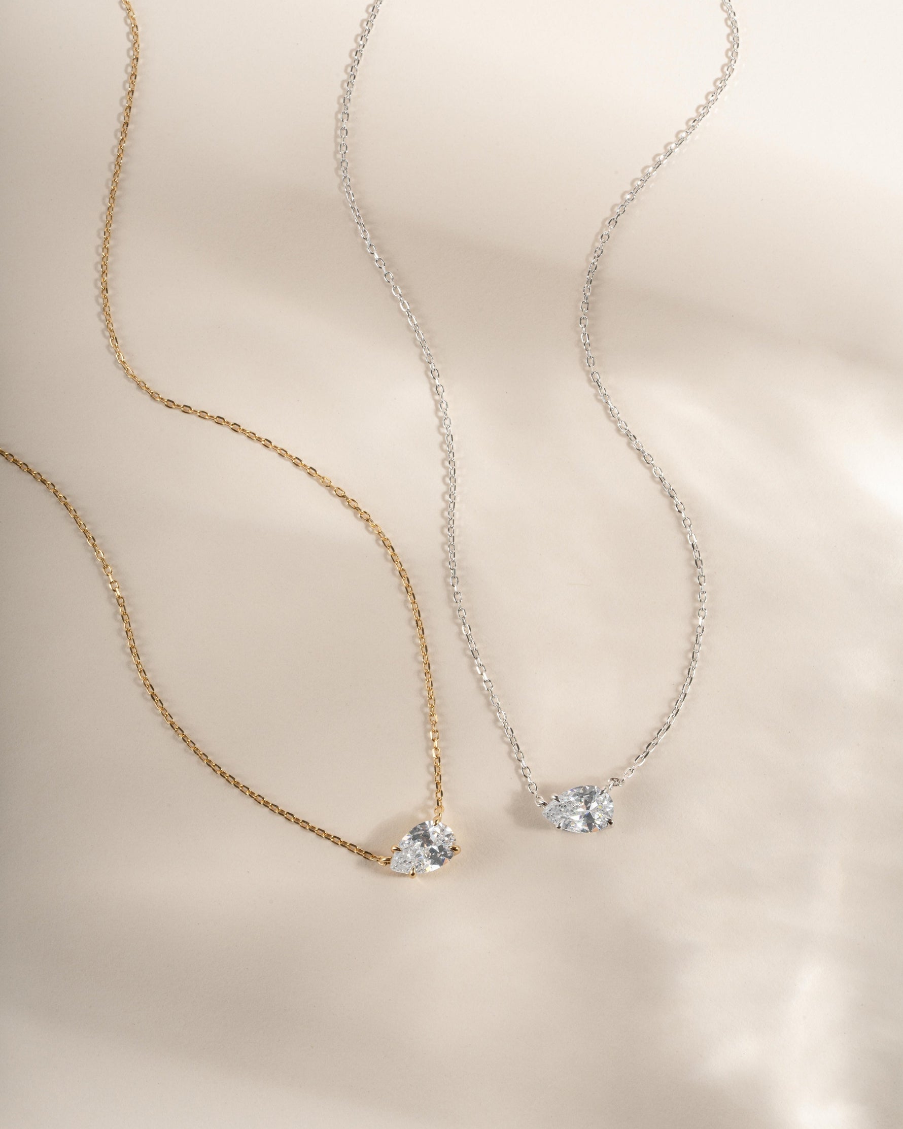 Two bridal necklaces, one gold chain and one silver chain with a teardrop diamond pendant