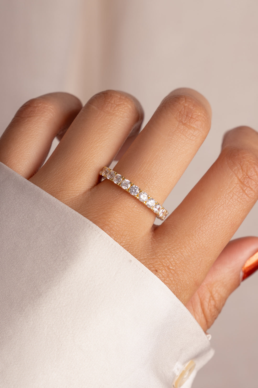 Model wearing engagement style wedding diamond band in gold. 