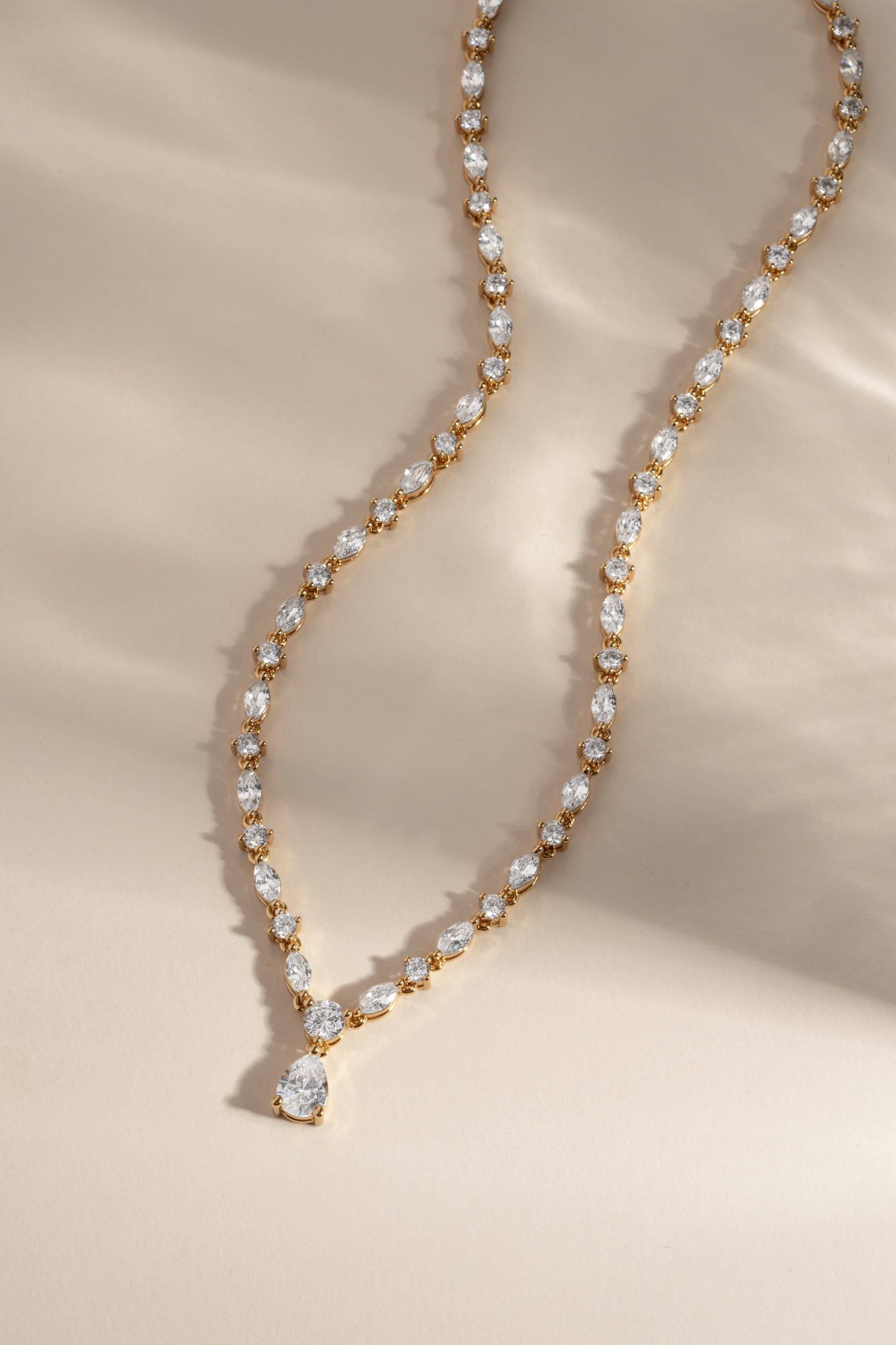 Gold necklace with cubic zirconia stones on a beige background