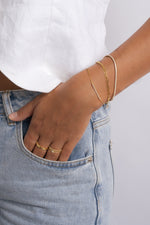dainty gold chain bracelets featuirng a pave bar, a chain bracelet set, and a delicate tennis bracelet on model