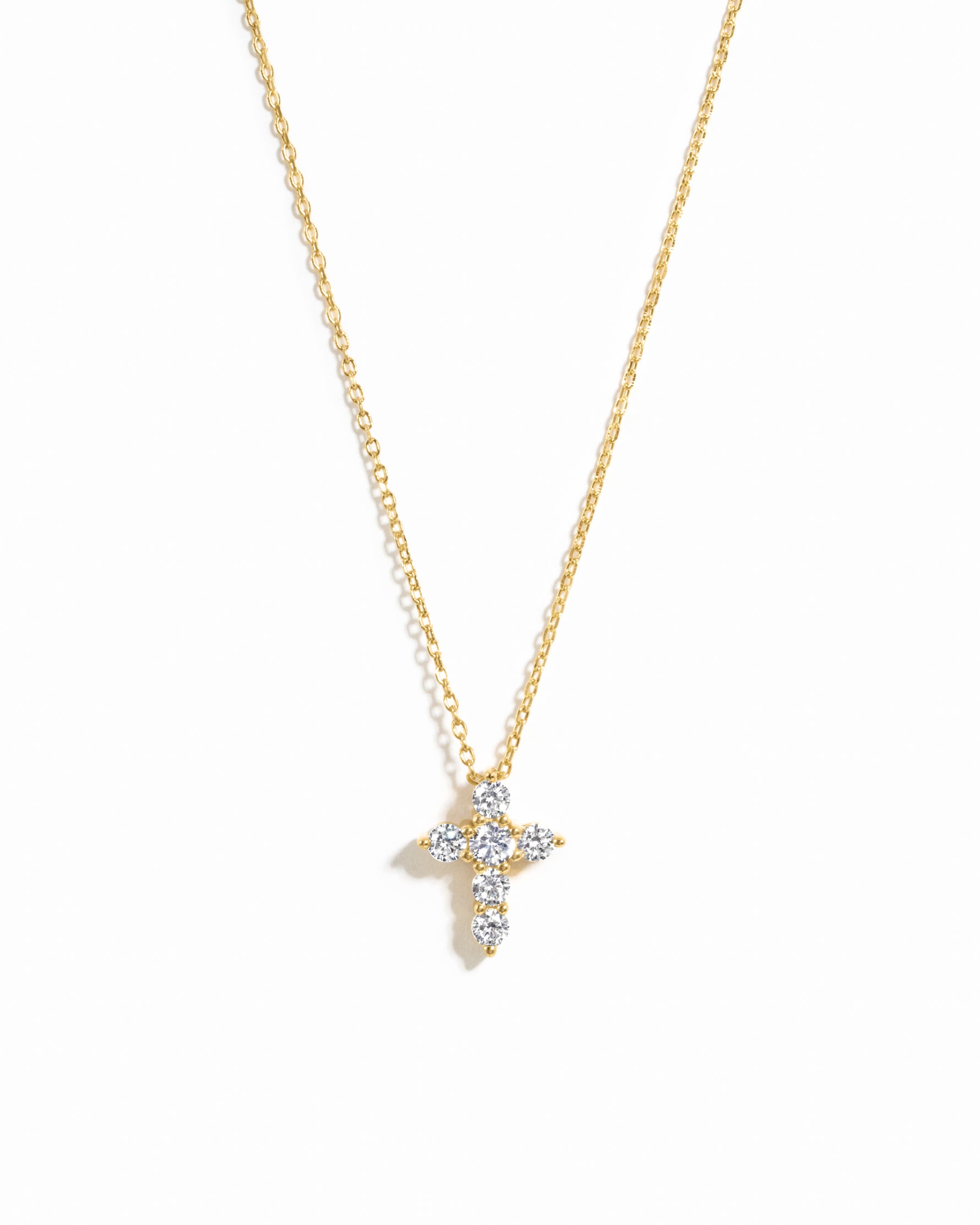 Gold necklace with a diamond cross pendant on a white background