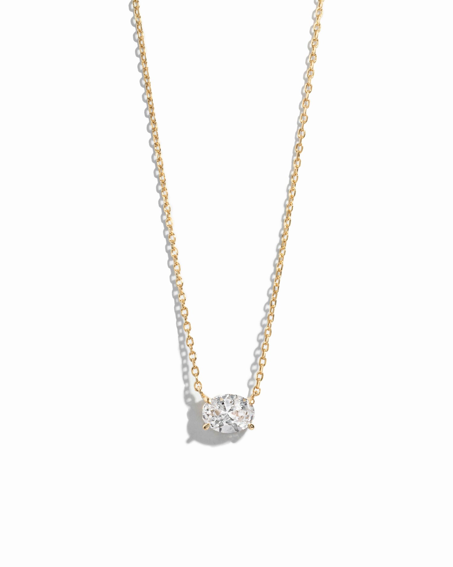 Gold necklace with a oval shaped diamond pendant on a white background