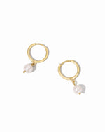 Gold hoop earrings with white pearls on a white background