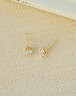 Pear diamond earrings on a beige fabric