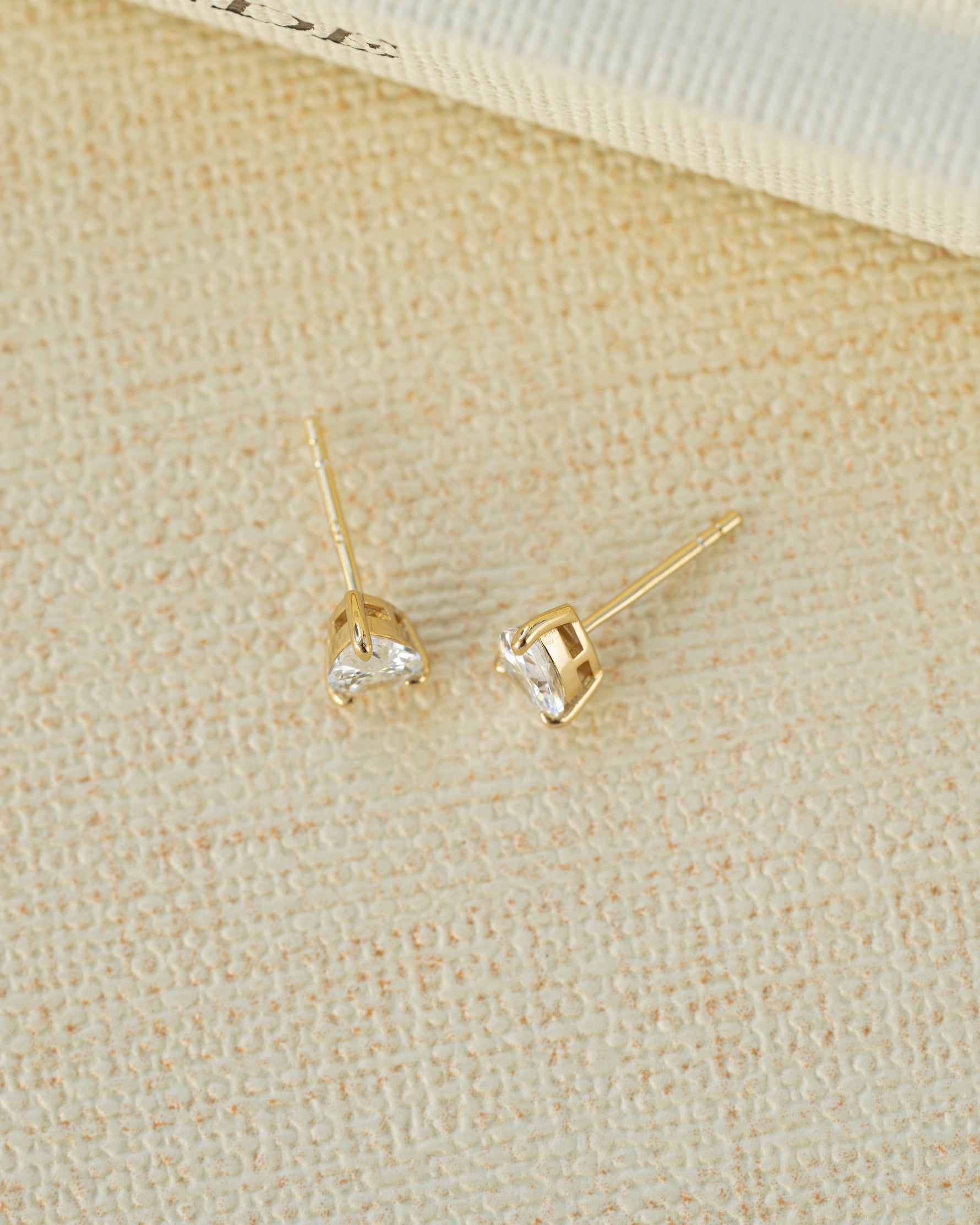 Pear diamond earrings on a beige fabric