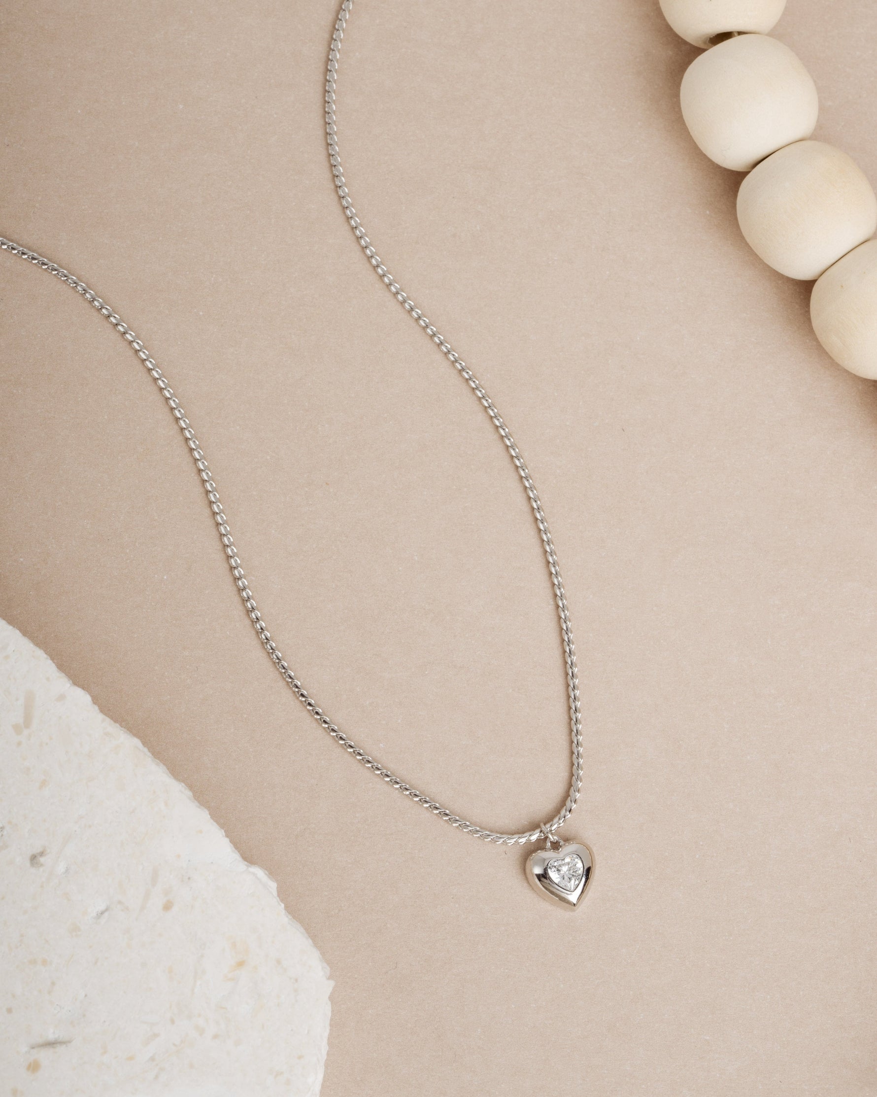 Silver diamond pendant love necklace on beige background 