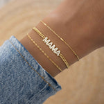 Model showcasing gold jewelry featuring charm bracelet with MAMA charm and gold chain 