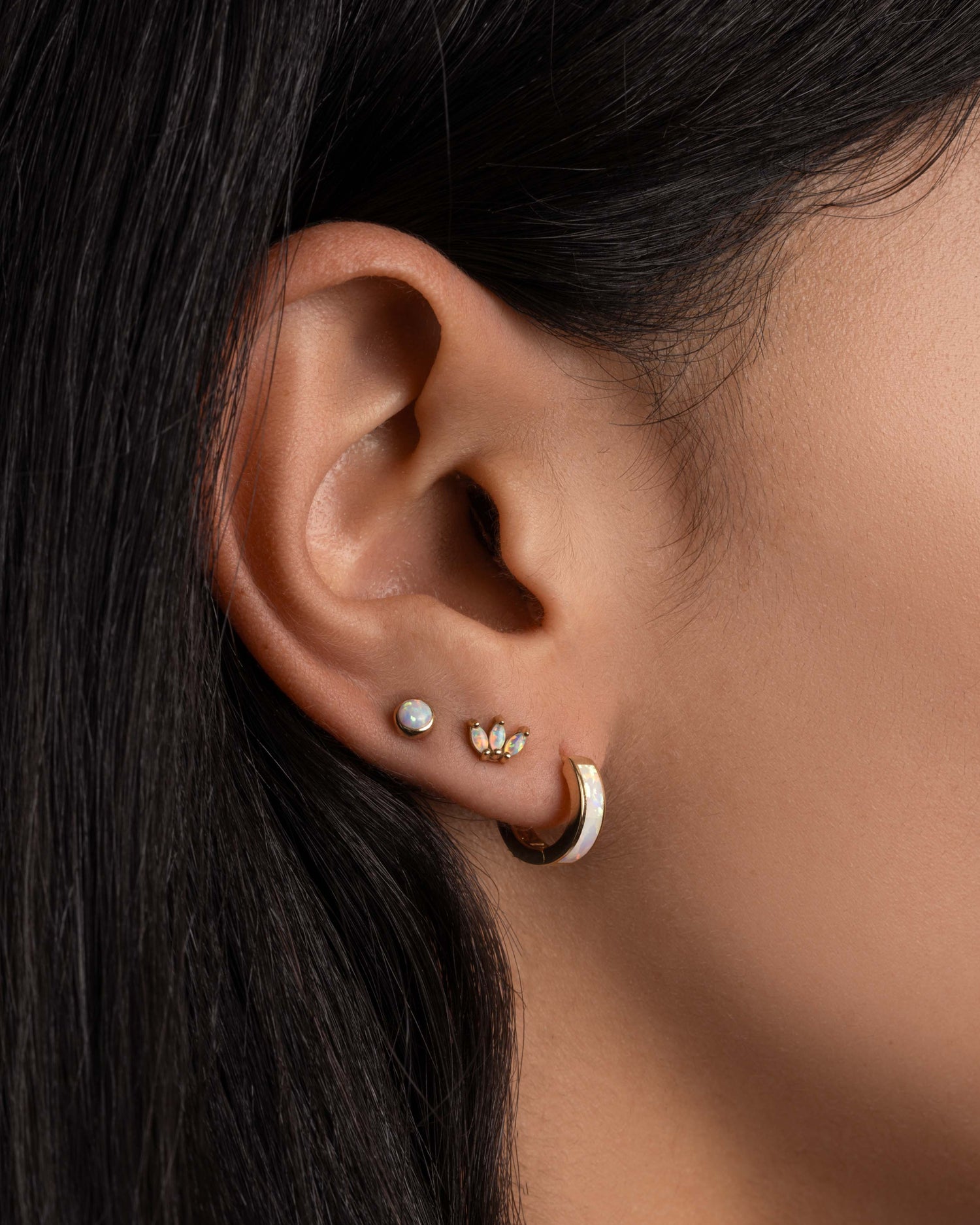 Model wearing dainty petal opal studs and opal huggies.