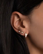Dainty opal earrings in models ear.