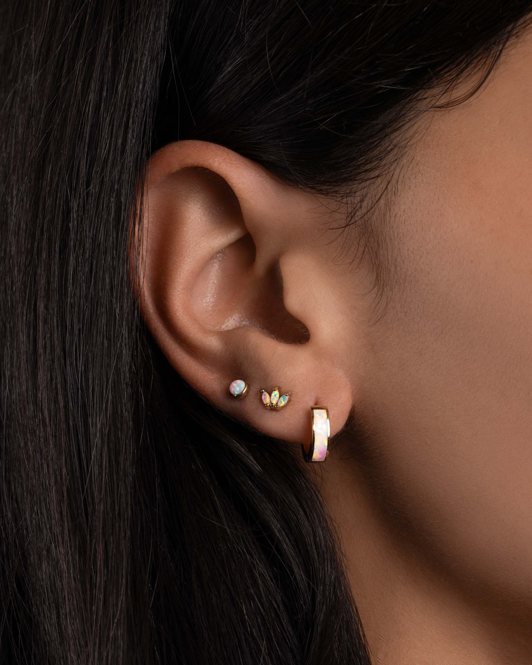 Dainty opal earrings in models ear.
