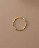 Gold plain beaded ring on a beige surface 
