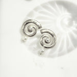 closeup image of silver spiral earrings with a freshwater pearl charm