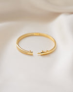 14k gold plated diamond bangle with box clasp closure on silk background