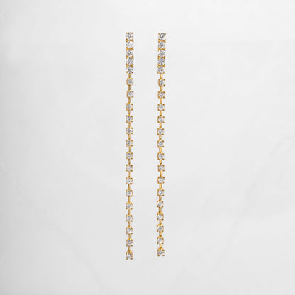 clse up of gold dangle earrings with a smooth, slender line of sparkling cubic zirconia, perfect for bridal earrings or wedding jewelry.